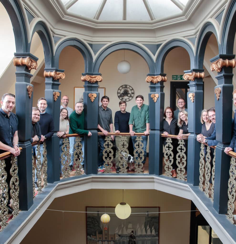 The TalkType team huddling around a staircase bannister, smiling at the camera.