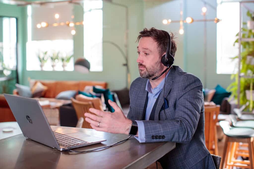 A photo of Chris who is delivering a live demo, wearing a suit and a headset.