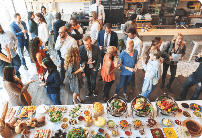 Group of people networking at a brunch, with lots of food on a table beside them